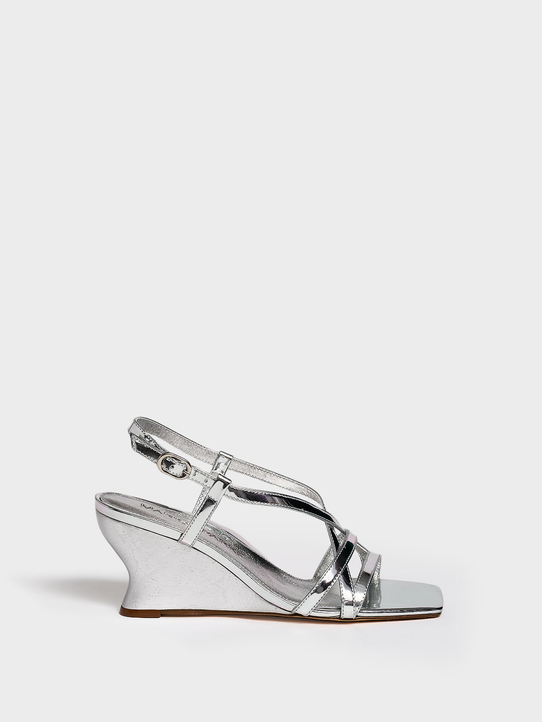 Profile view of a silver metallic leather strappy sandal with a sculptural wedge.
