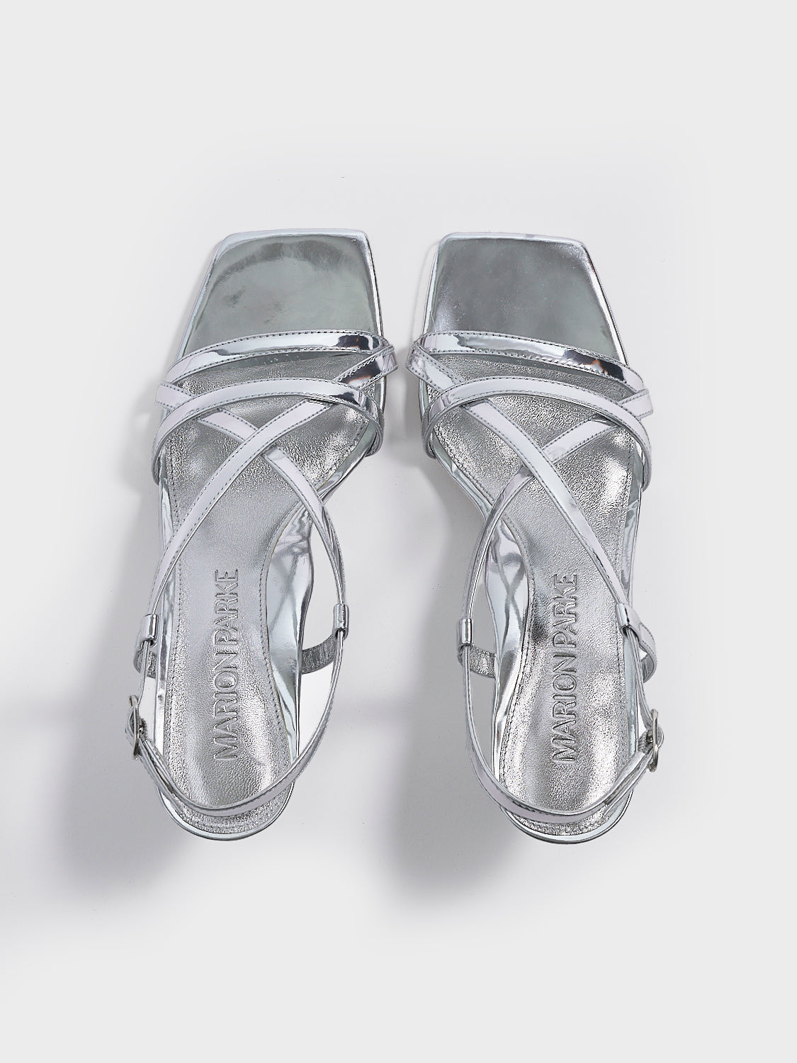 Top view of a pair of silver metallic leather strappy sandals with a sculptural wedge.