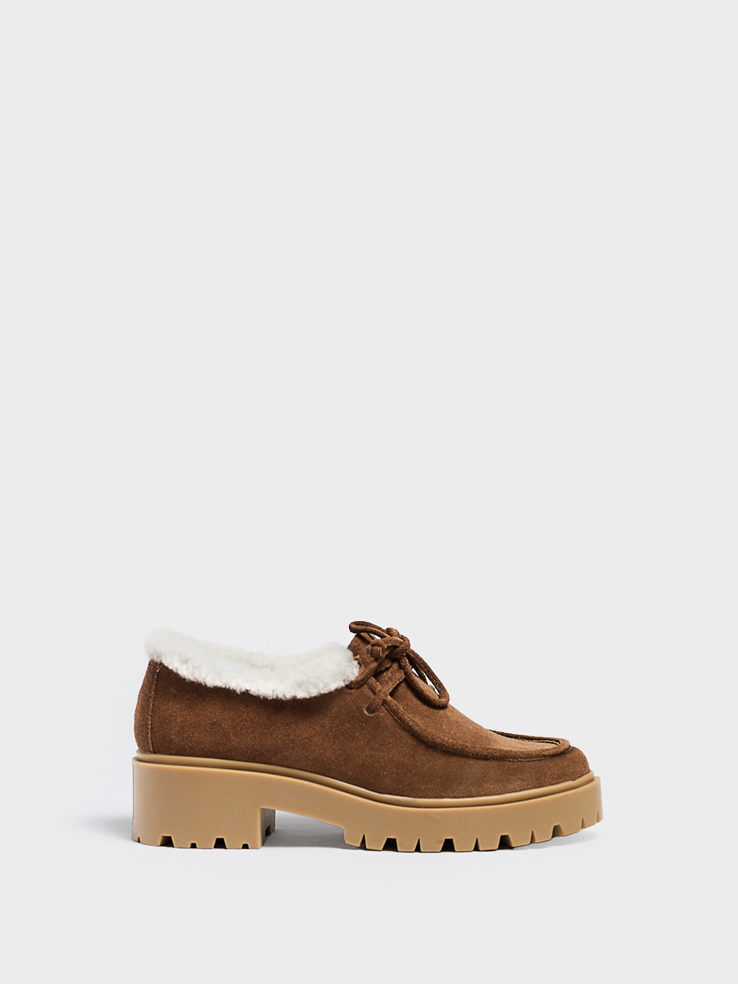 Profile view of a mocha suede lug sole loafer with shearling lining and tie details.