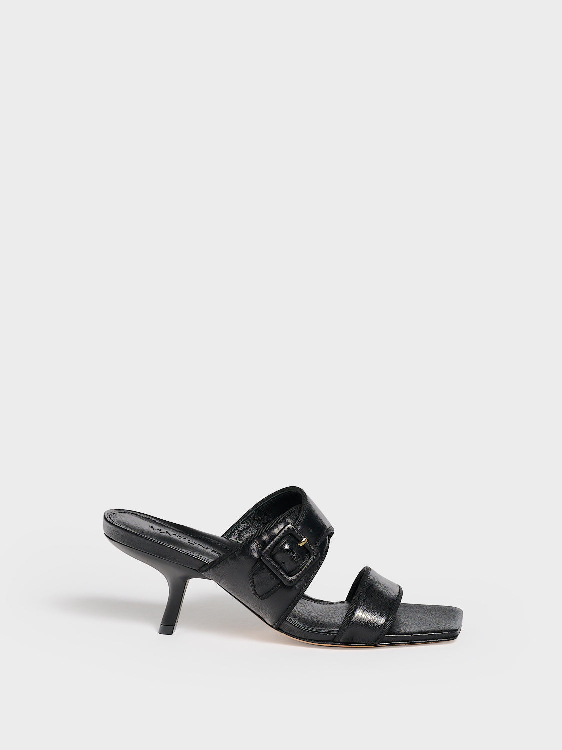 Profile view of a black leather slide kitten heel sandal with a buckle detail.