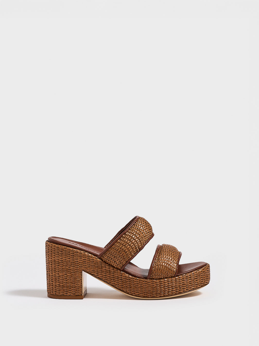 Profile view of a dark brown raffia platform sandal with a  leather trim and puffed straps. 