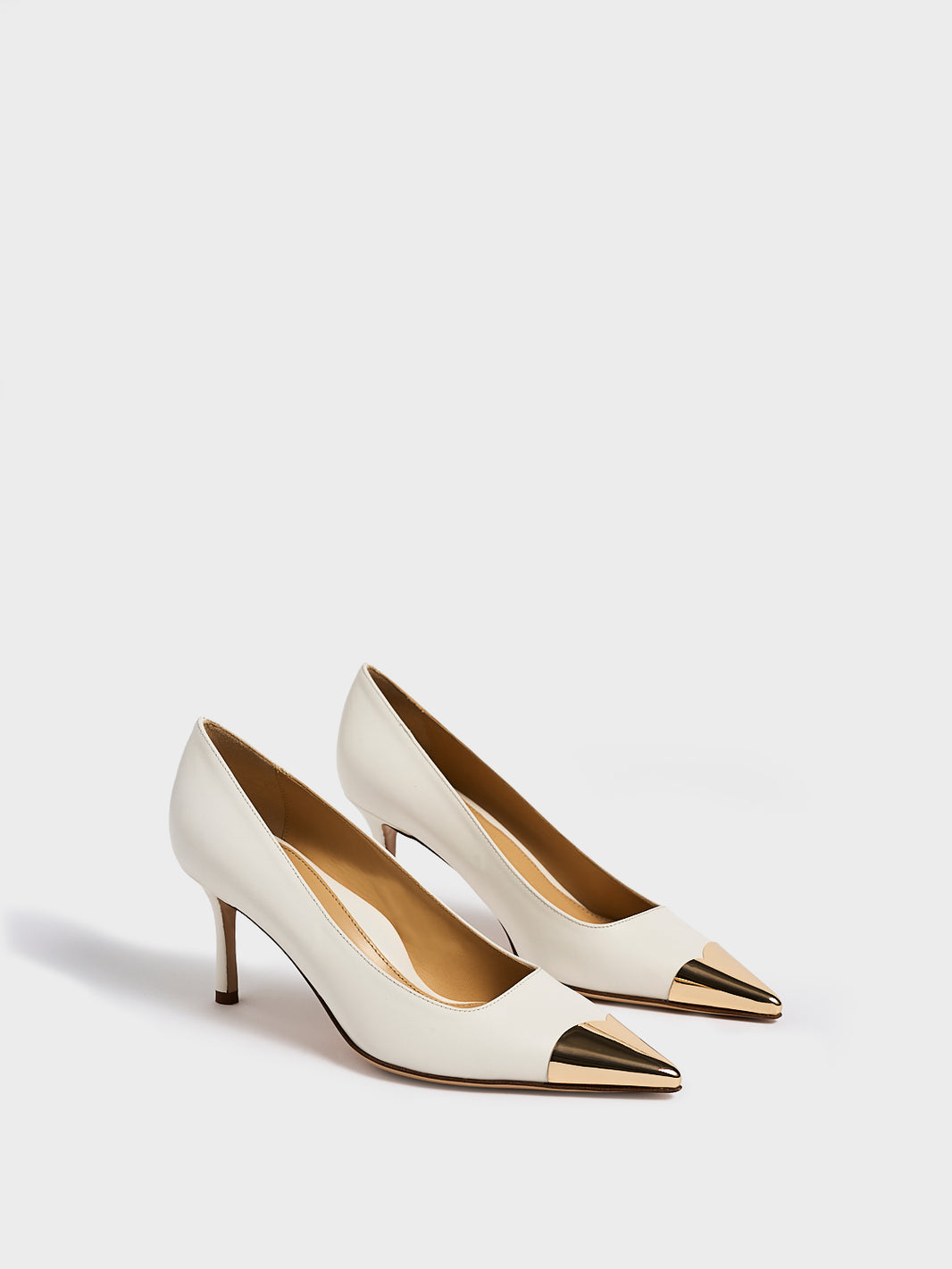 Angle view of a pair of white leather stiletto heel pumps with a gold metallic toe cap and a pointed toe.