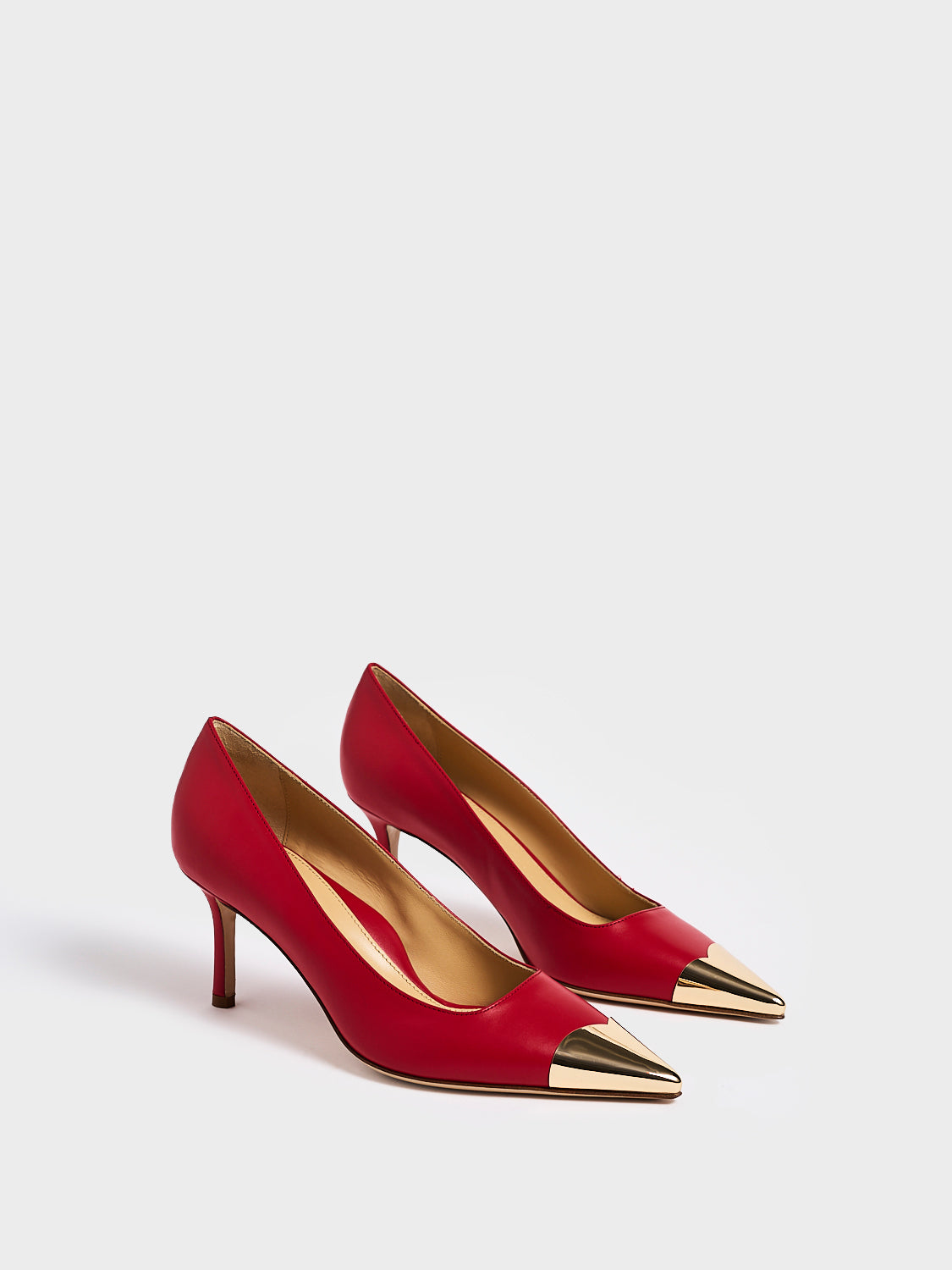 Angle view of a pair of red leather stiletto heel pumps with a gold metallic toe cap and a pointed toe.