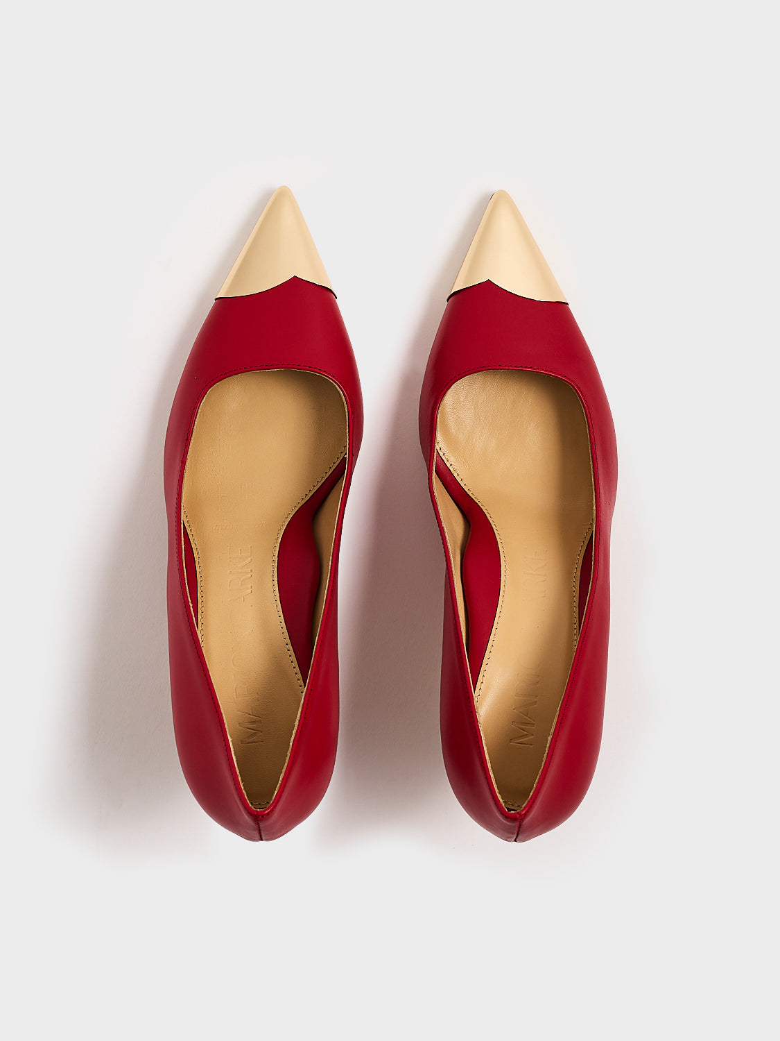 Top view of a pair of red leather stiletto heel pumps with a gold metallic toe cap and a pointed toe.