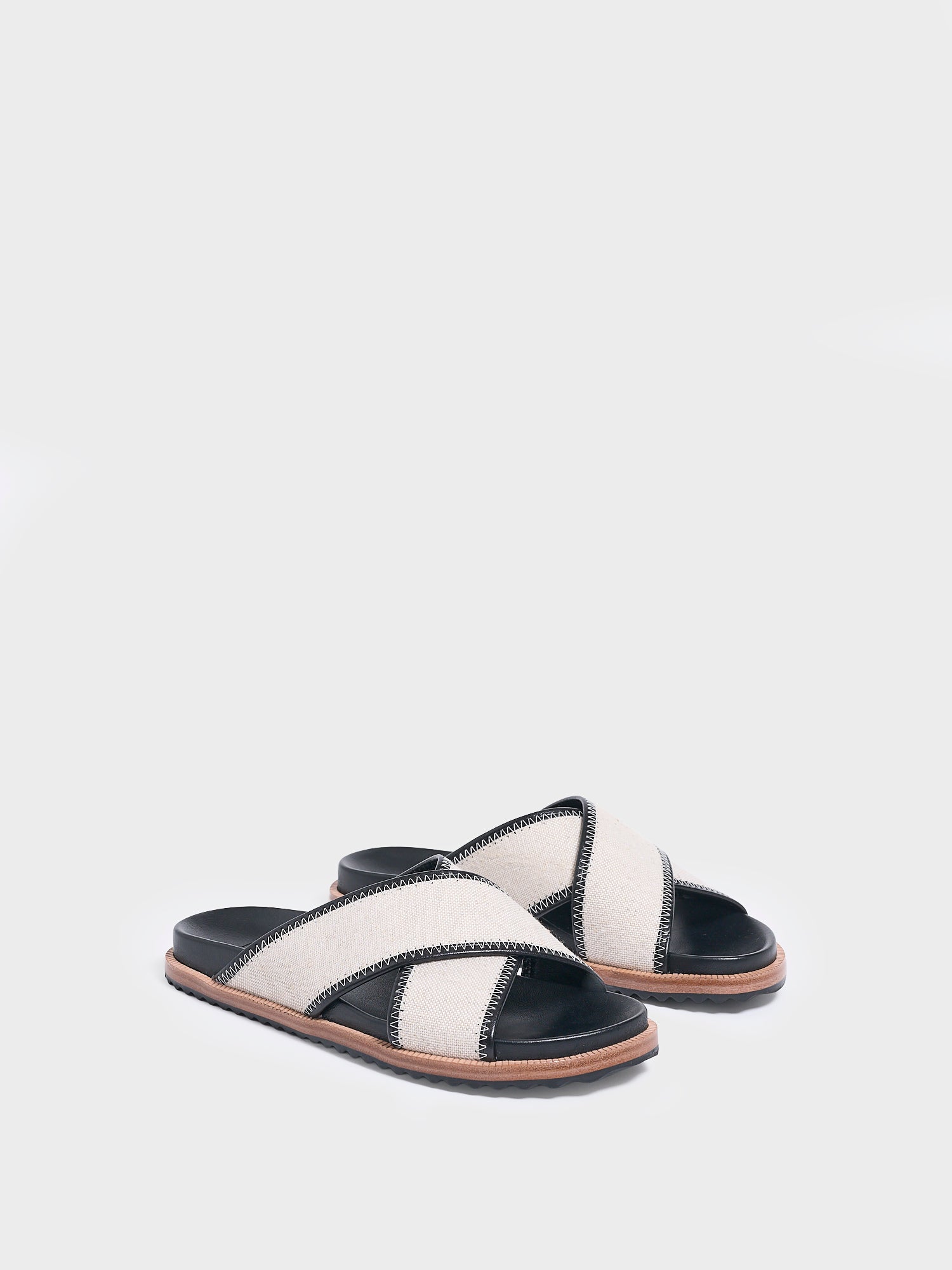 Angle view of a pair of salt and pepper linen molded footbed slide sandals.