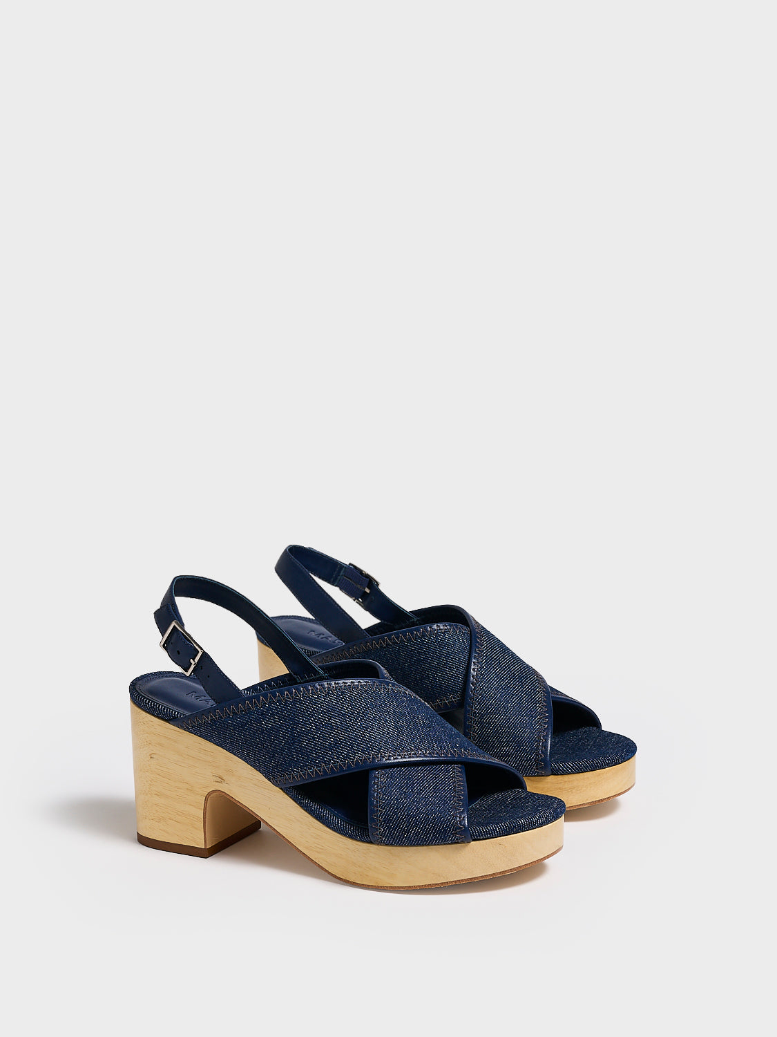Angle view of a pair of navy denim platform sandals with an adjustable back strap.