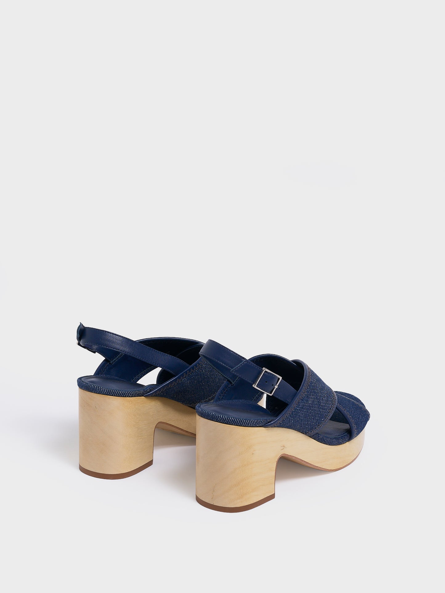 Back view of a pair of navy denim platform sandals with an adjustable back strap.