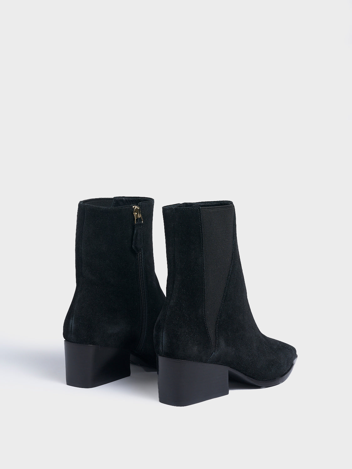 Back view of a pair of black suede chelsea boot with a zipper closure, square toe, and block heel. 