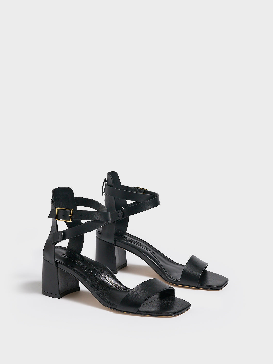 Angle View of a pair of black leather block heel sandals with an adjustable ankle strap design.