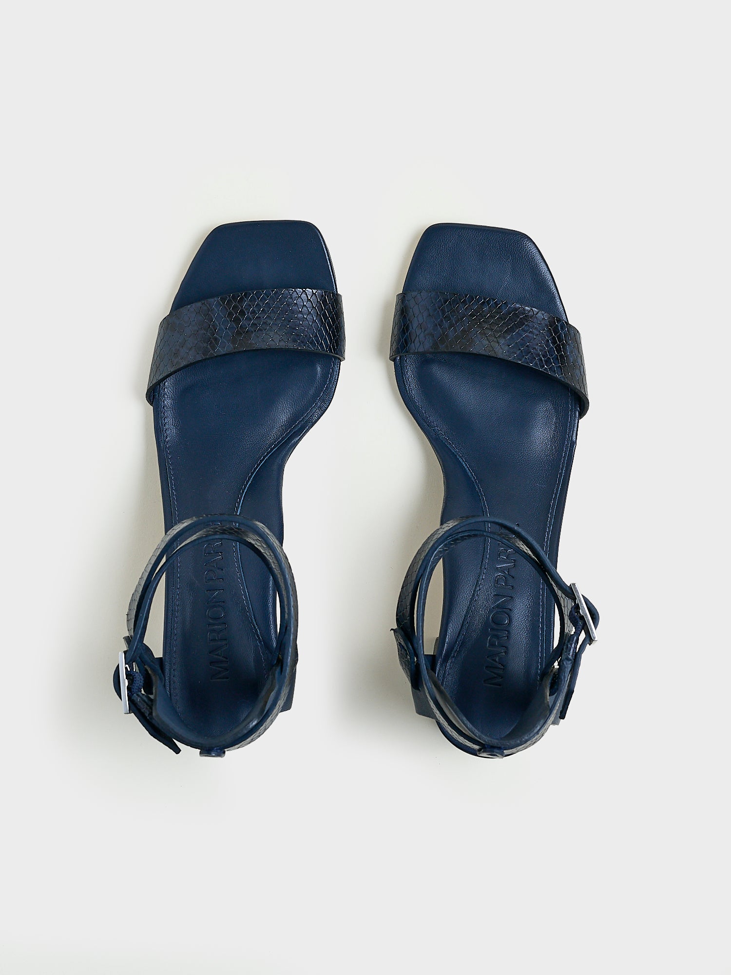 Top View of a pair of navy python leather block heel sandals with an adjustable ankle strap design.