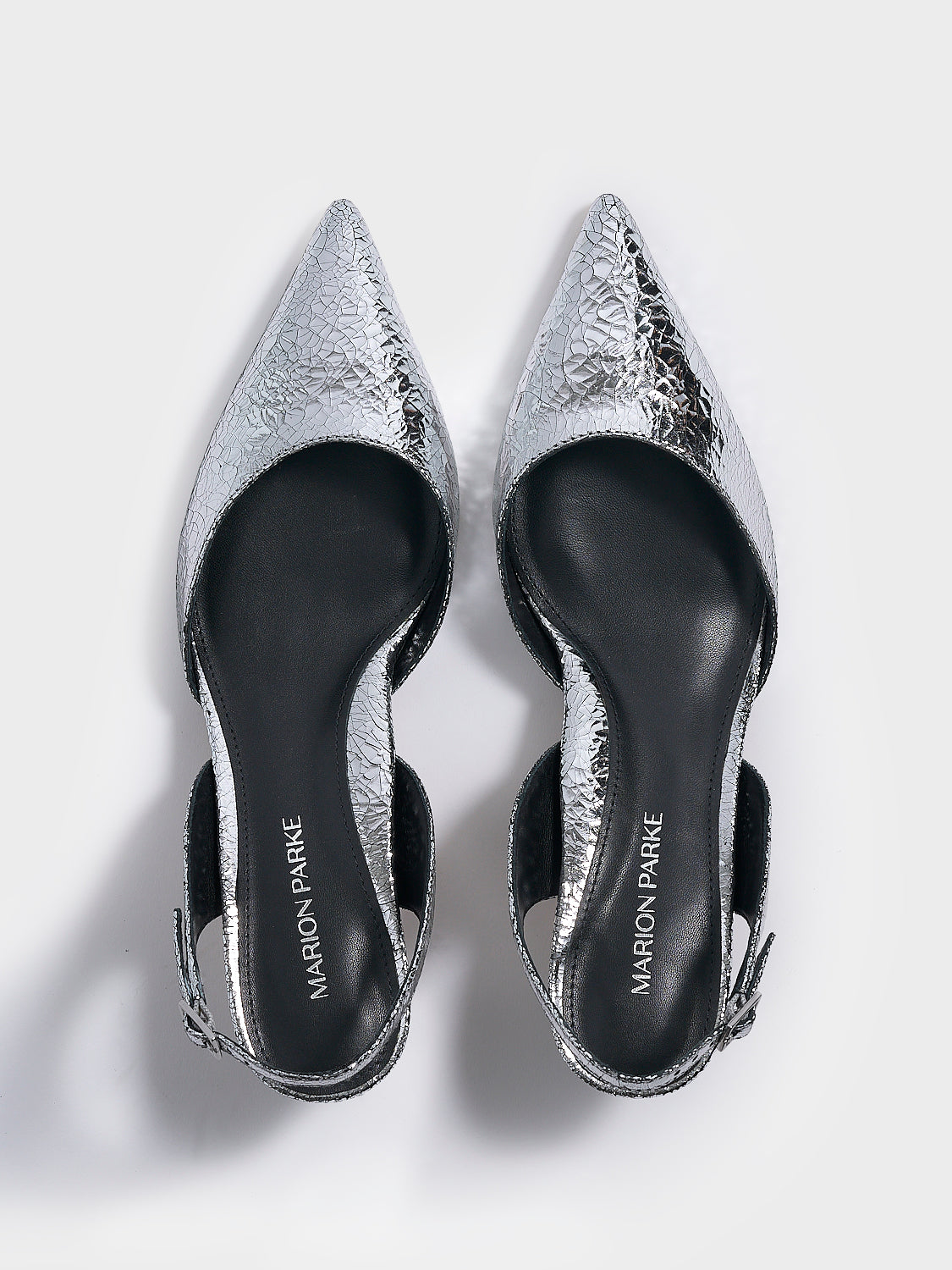 Top view of a pair of silver metallic leather kitten heel slingbacks with a pointed toe.