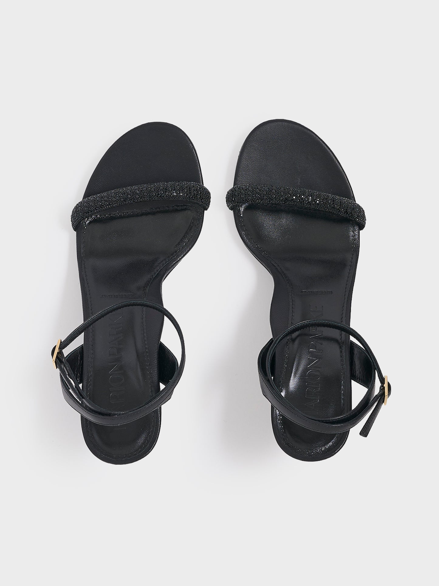Top view of a pair of black leather high heel sandals with a crystal embellished toe strap and adjustable ankle strap.