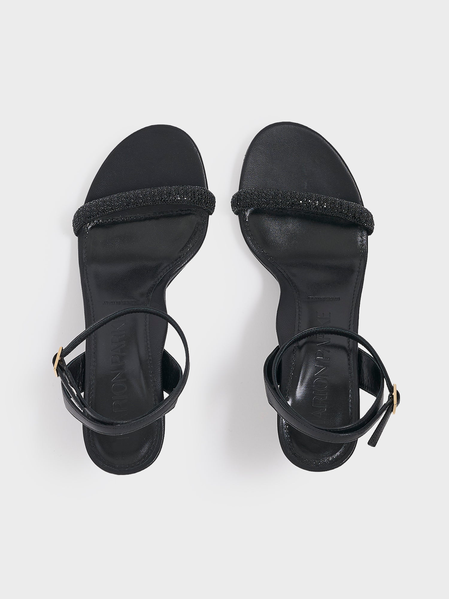 Top view of a pair of black leather high heel sandals with a crystal embellished toe strap and adjustable ankle strap.