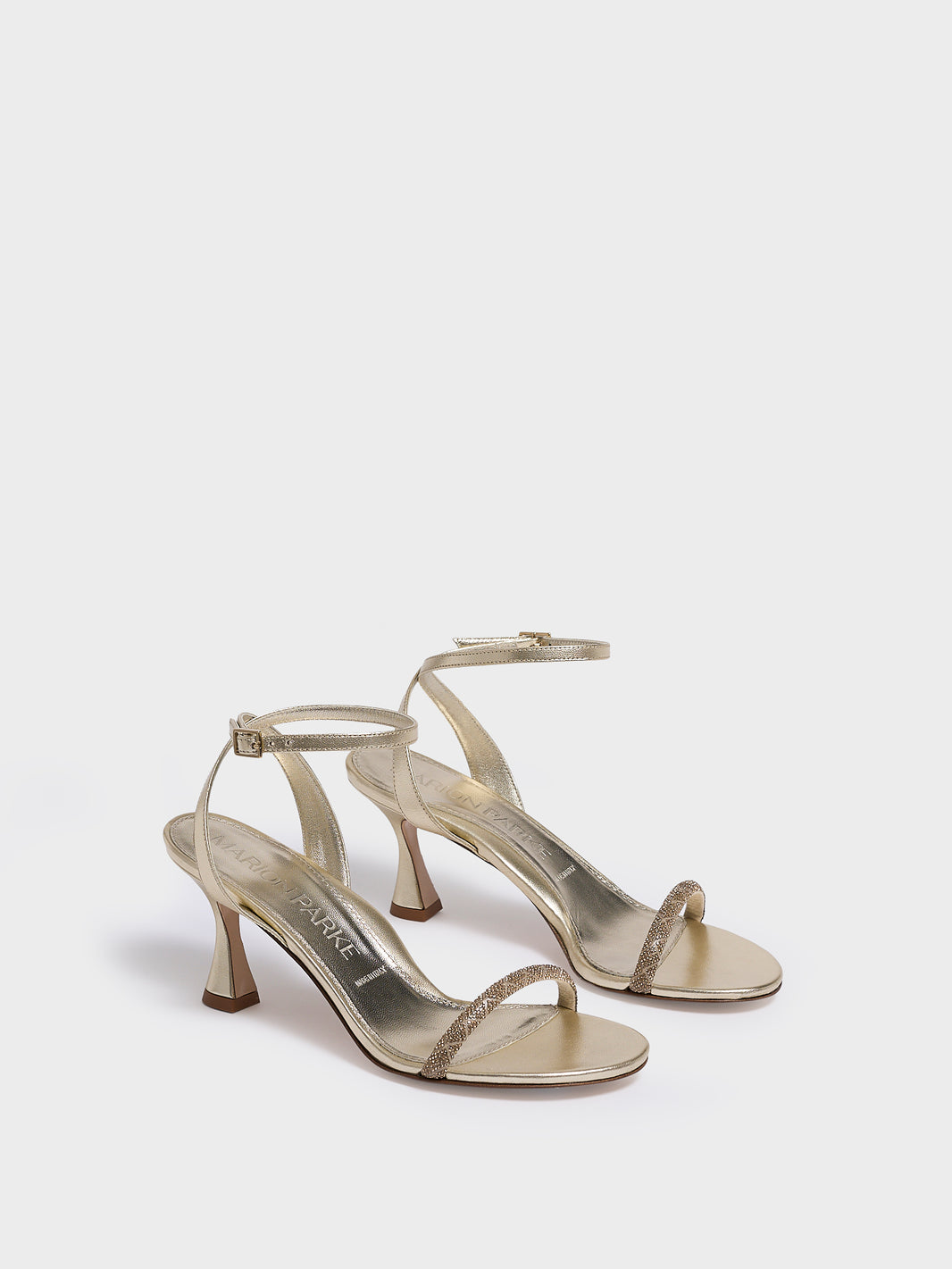 Angle view of a pair of gold metallic leather high heel sandals with a crystal embellished toe strap and adjustable ankle strap.