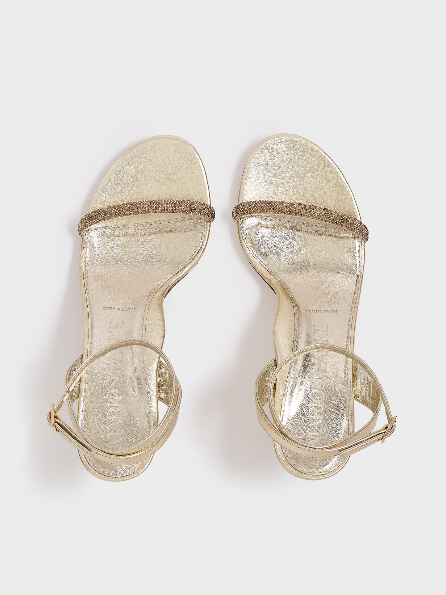 Top view of a pair of gold metallic leather high heel sandals with a crystal embellished toe strap and adjustable ankle strap.