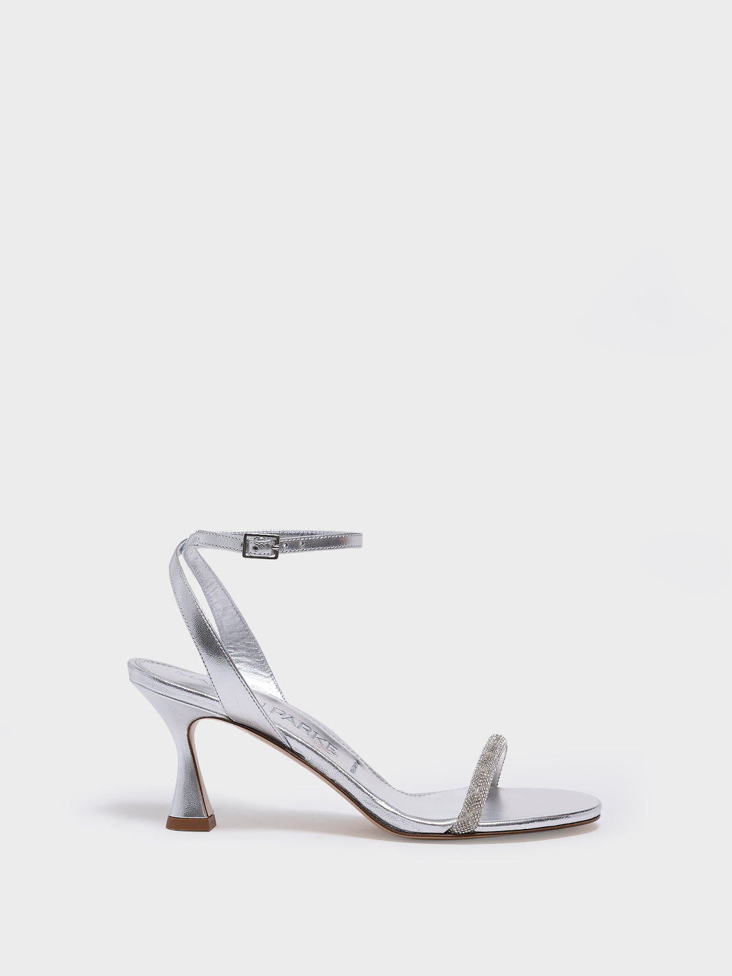Profile view of an silver metallic leather high heel sandal with a crystal embellished toe strap and adjustable ankle strap.