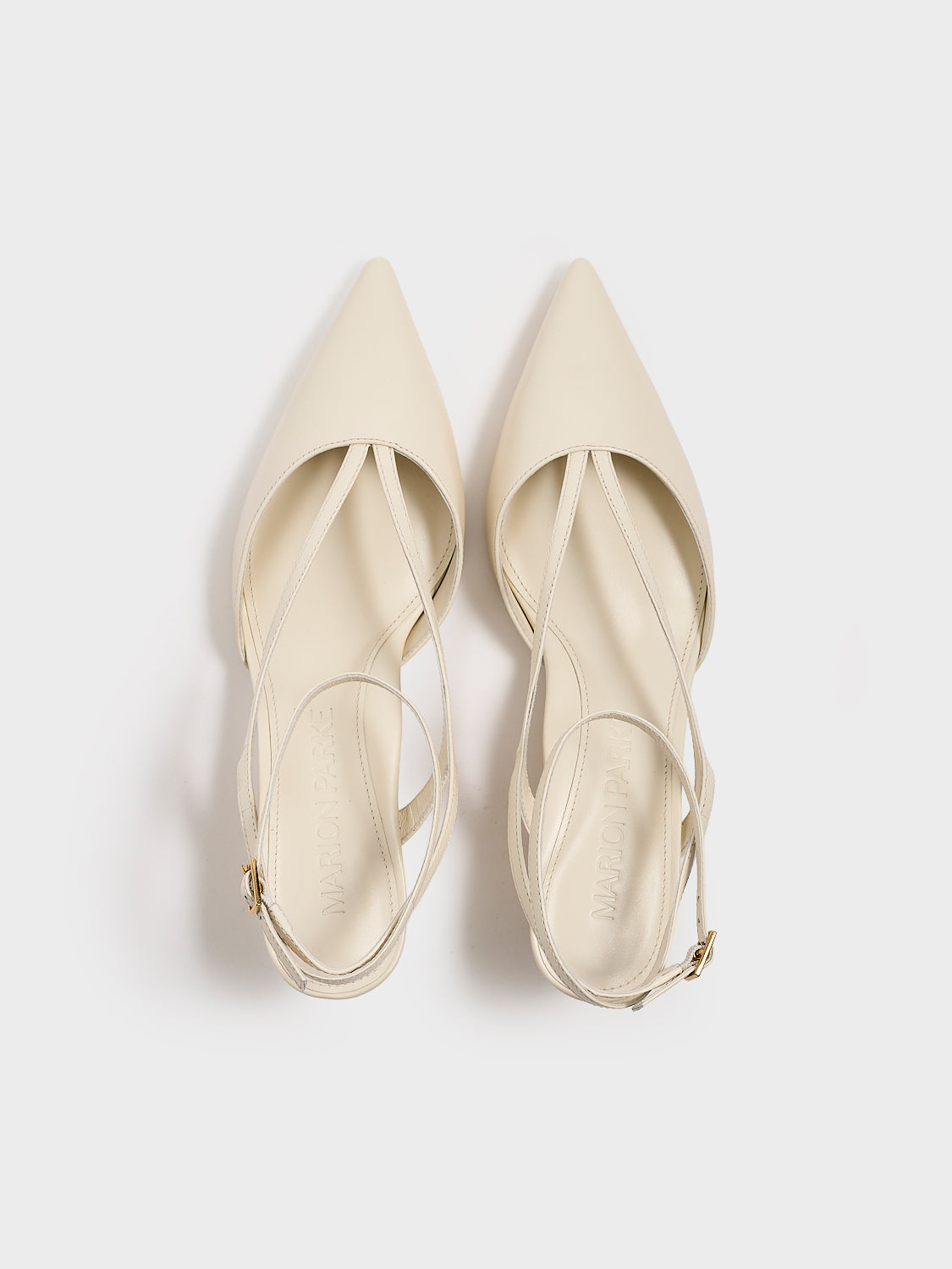 Top view of a pair of  ivory leather kitten heels with sculpted strap design and an adjustable ankle strap.