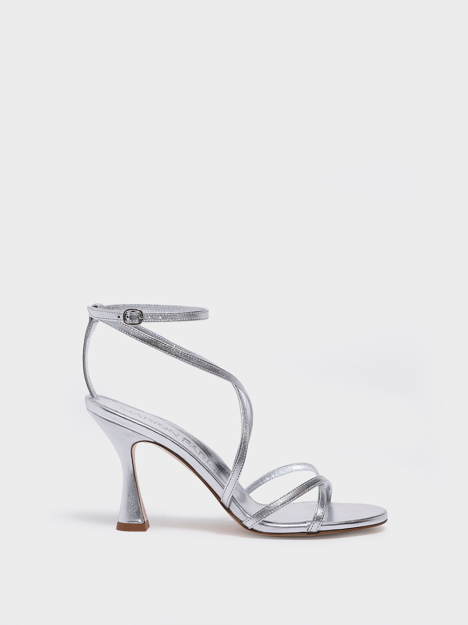 Profile view of a silver leather high heel strappy sandal with an ankle strap detail. 