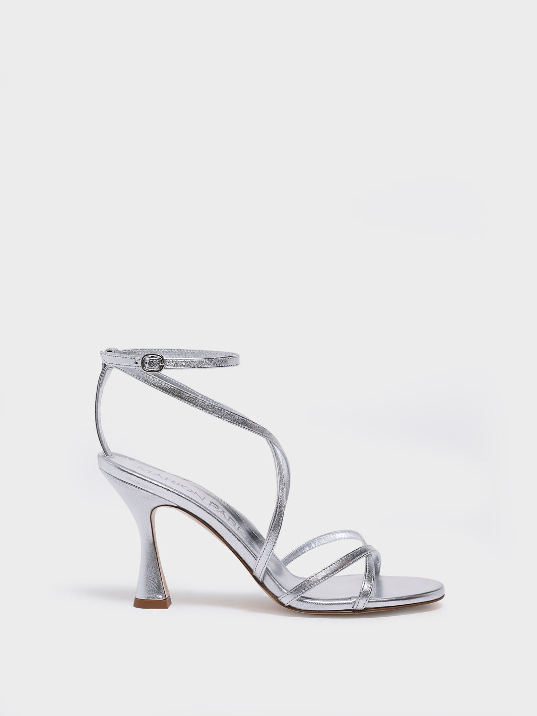 Profile view of a silver leather high heel strappy sandal with an ankle strap detail. 