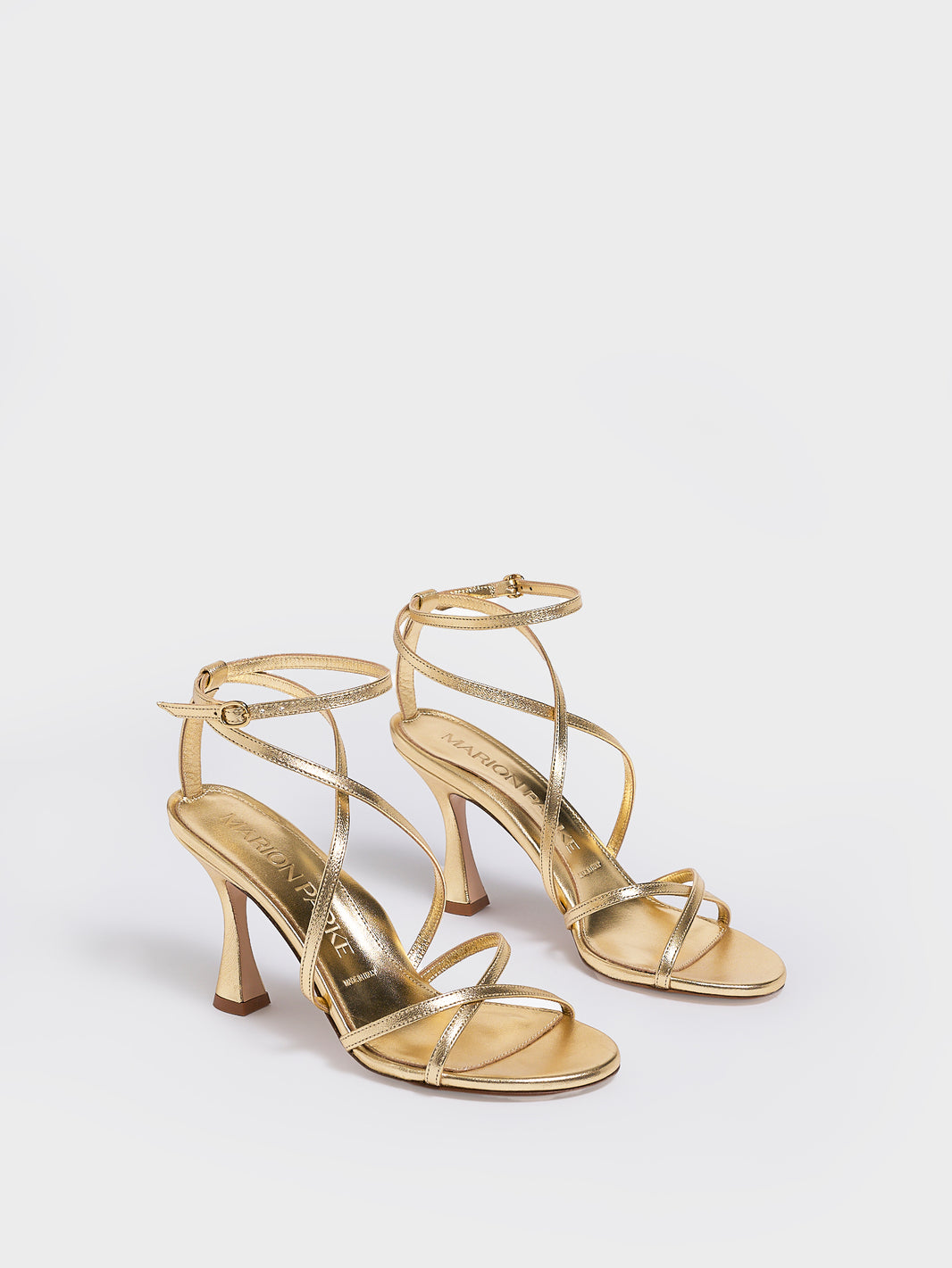 Angle view of a pair of black leather high heel strappy sandals with an ankle strap detail. 