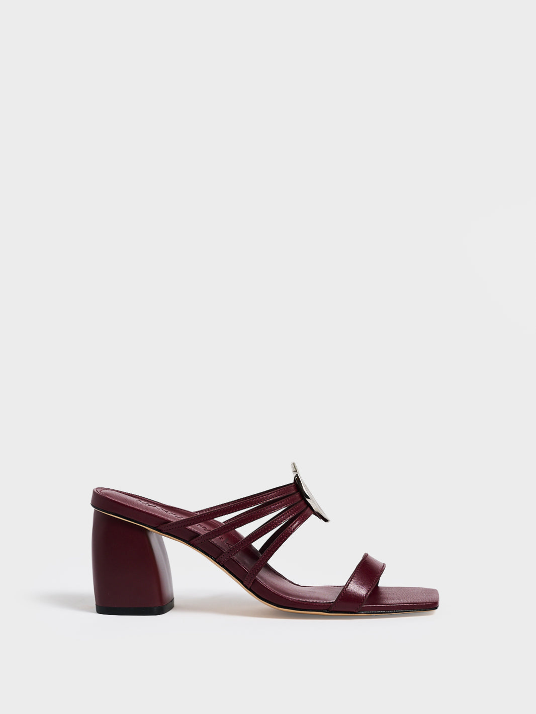 Profile view of a burgundy leather block heel sandal with a strappy design and sculpted silver hardware.