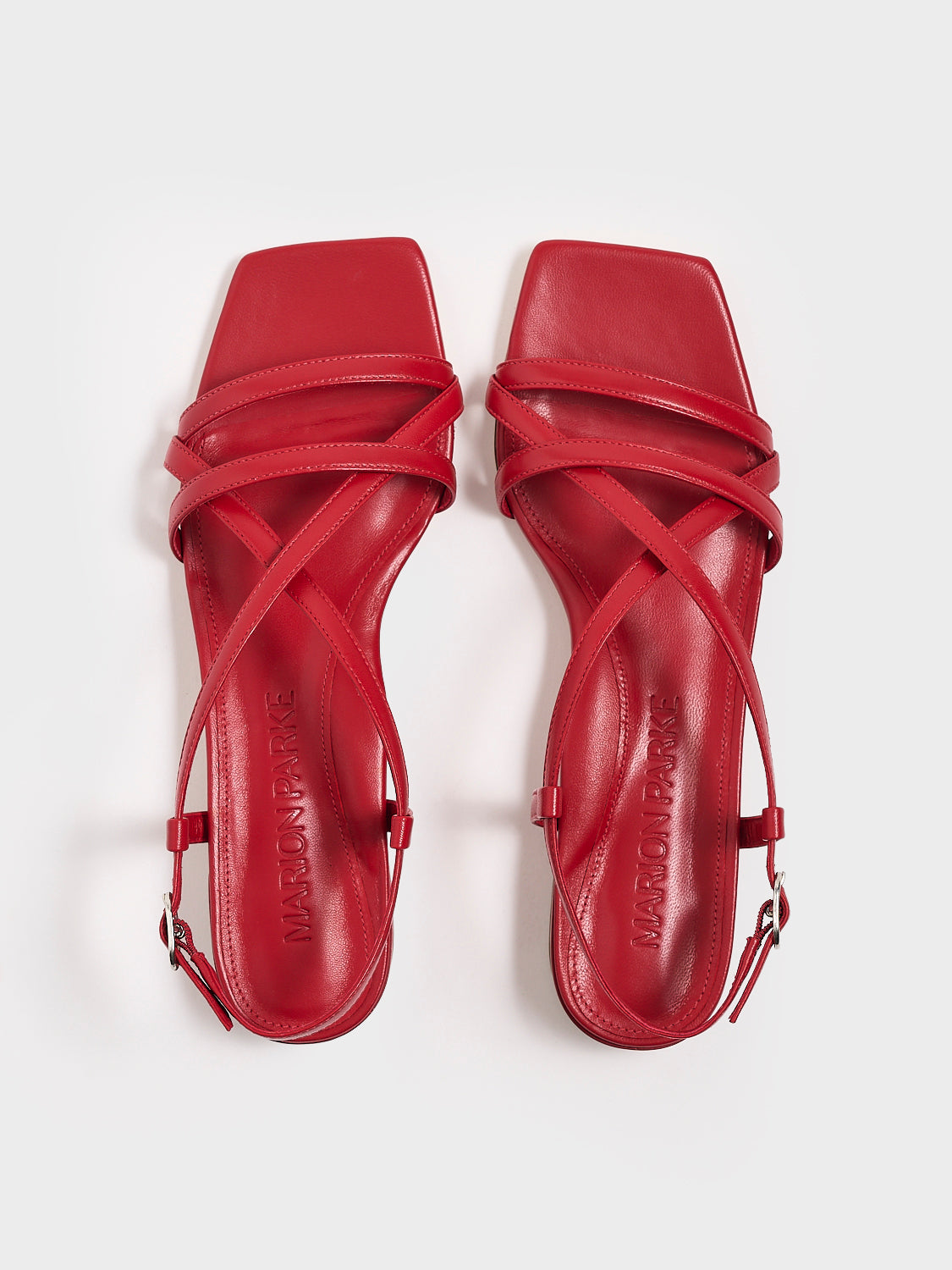Top view of a pair of lipstick red leather flat strappy sandals.