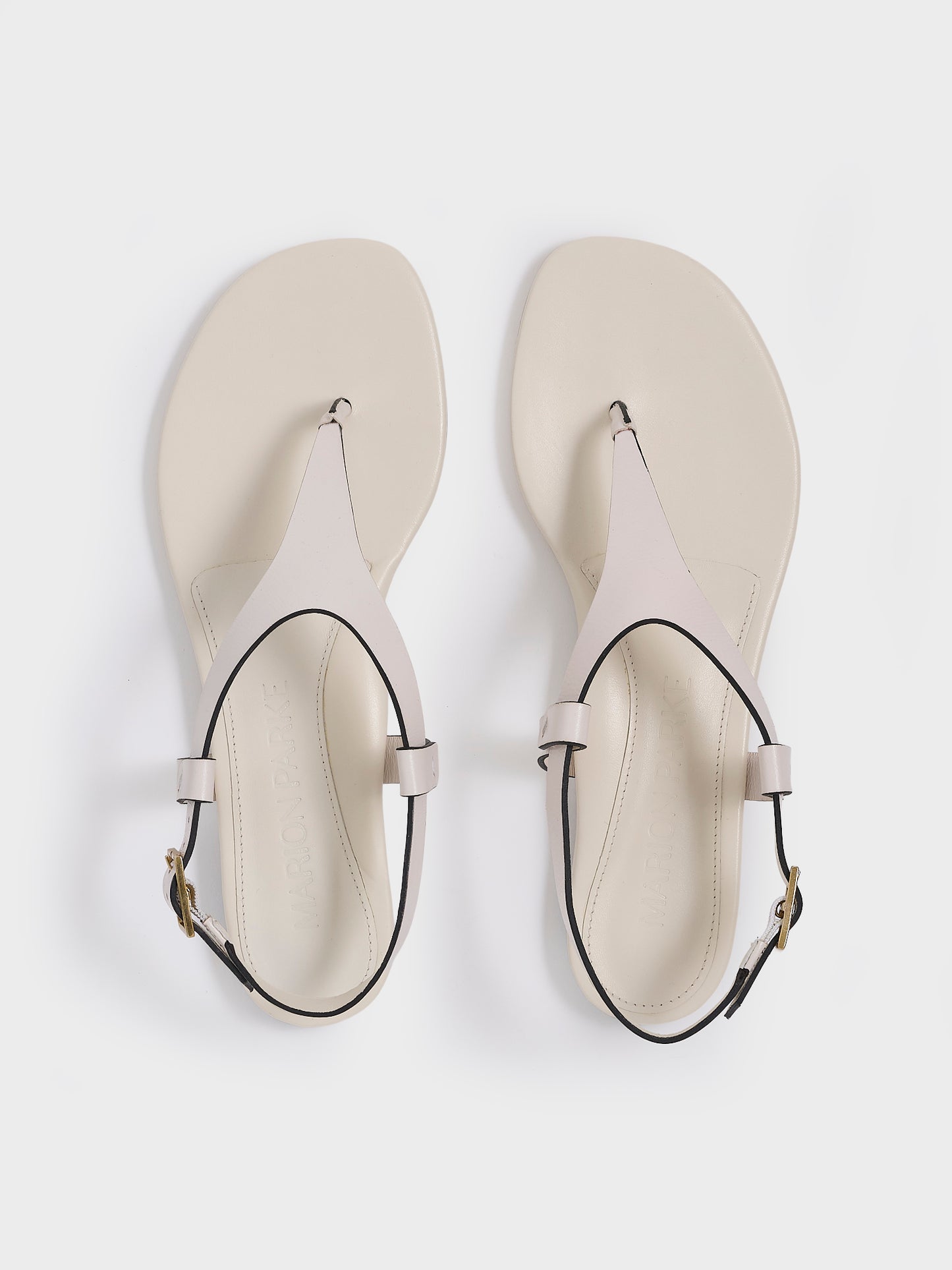 Top view of a pair of ivory leather thong sandals with a clean design and adjustable ankle strap. 
