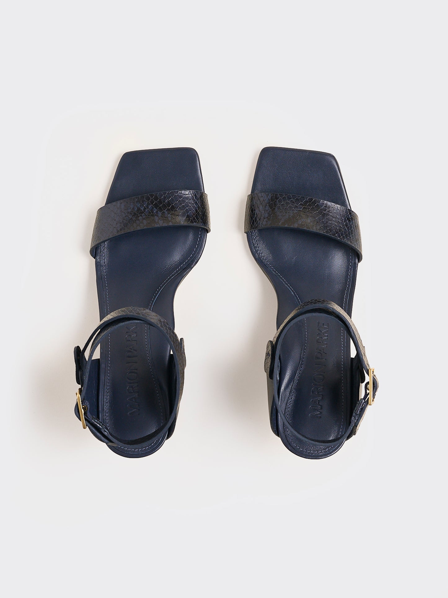 Top view of a pair of navy python leather and suede high heel sandals with a sculptural design and adjustable ankle strap. 