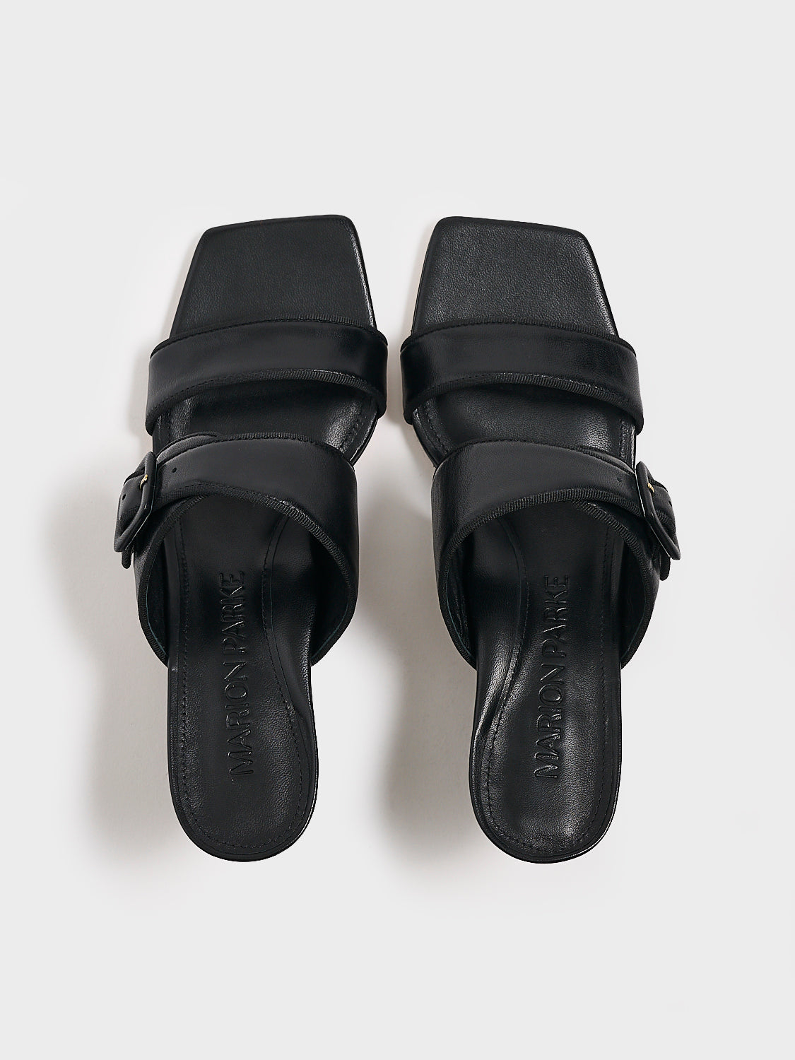 Top view of a pair of black leather slide kitten heel sandals with a buckle detail.