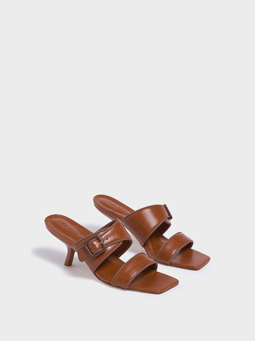 Angle view of a pair of chestnut leather slide kitten heel sandals with a buckle detail.