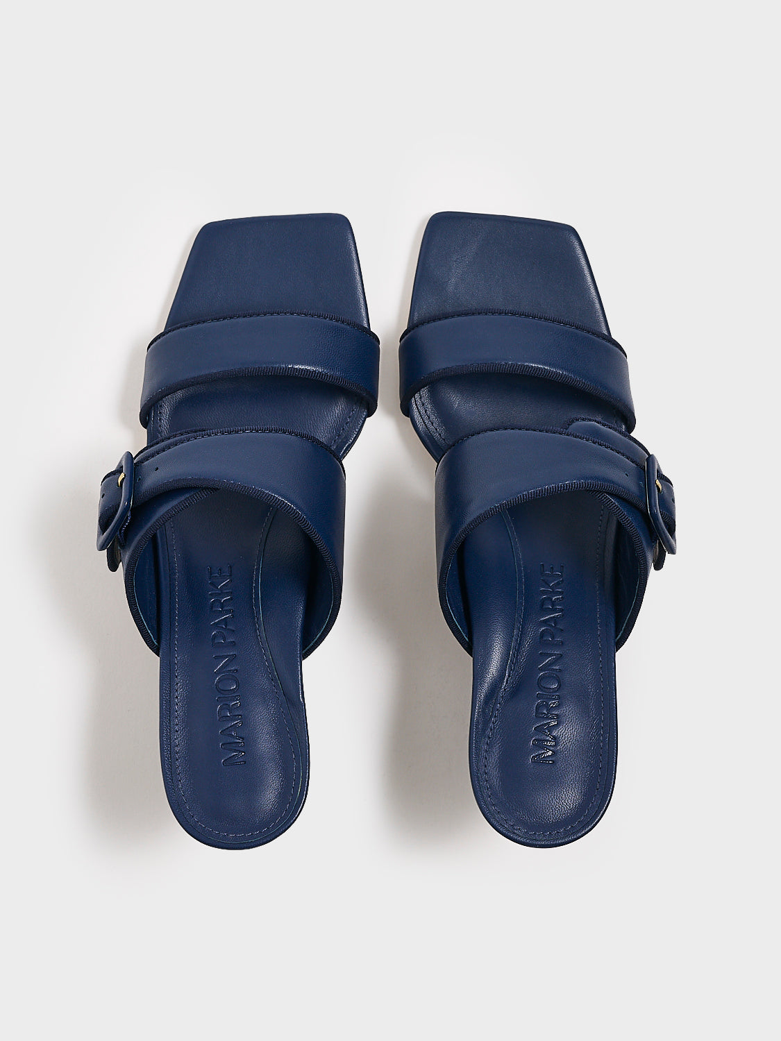 Top view of a pair of navy leather slide kitten heel sandals with a buckle detail.